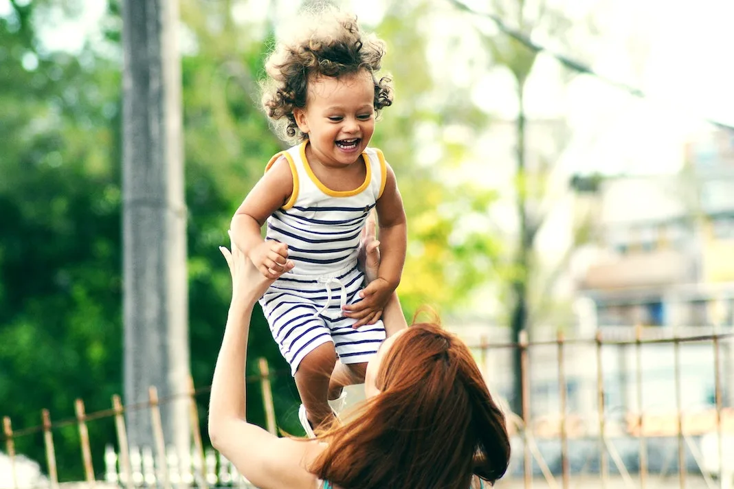 mother throwing her baby in the air playfully