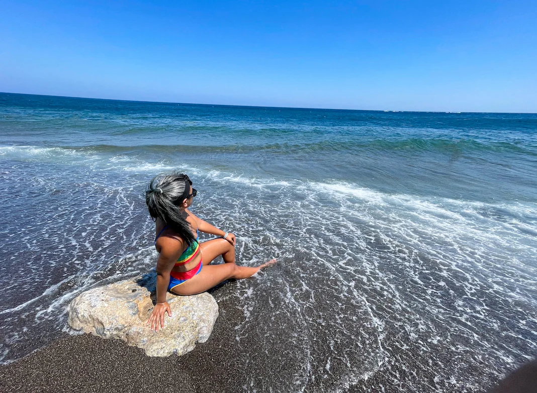 wearing beach riot bikini at the black sand beach in Santorini